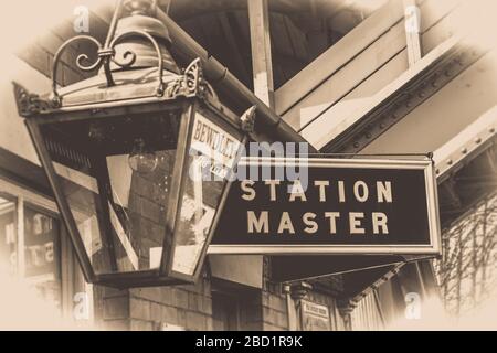 Old-fashioned, sepia vintage station master sign & traditional lamp on platform at Bewdley vintage train station, Severn Valley Railway UK. Stock Photo