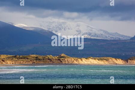 Newborough beach and sand dunes with a snow covered Mount Snowdon in the background, Anglesey Stock Photo