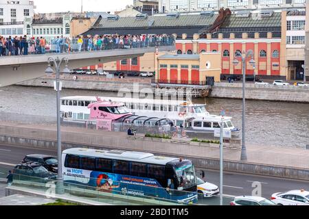 Moscow, Russia - July 8, 2019: View of the floating bridge over which people walk in Zaryadye park. Pleasure boats sail under floating bridge above ri Stock Photo