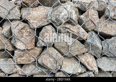 textural background - granite stone behind a mesh netting, wall. Stock Photo