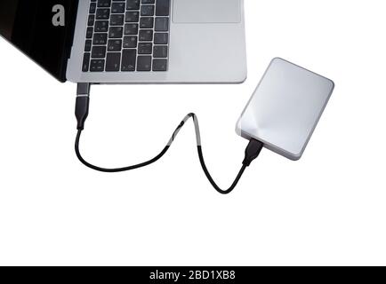 Silver external hard disk drive connected to a laptop computer for data backup. Top view, isolated on white. Stock Photo