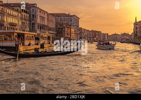 A gondolier steers his gondola on The Grand Canal near Rialto in the golden light of the late afternoon setting sun , Venice, Italy Stock Photo