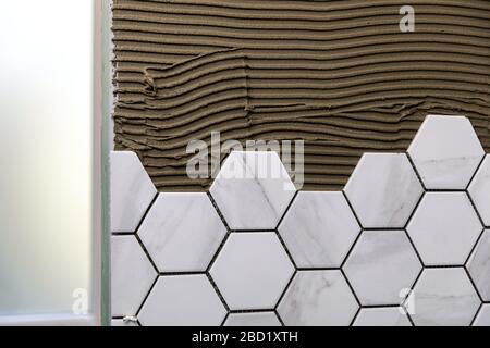 tiling - laying white marble texture hexagon tiles on the wall Stock Photo