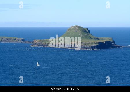 Yacht sailing past Bac Mor, from Lunga, Treshnish Isles, Hebrides, Scotland Stock Photo