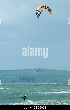 Garrettstown, West Cork, Ireland. 6th Apr, 2020. A kite surfer takes off during the strong winds and big waves at Garrettstown Beach whilst observing the Government's social distancing guidelines during the Covid-19 pandemic. Credit: Andy Gibson/Alamy Live News Stock Photo