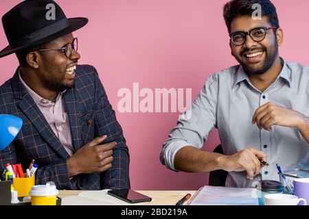 Two colleagues working together, discussing new project, making financial report, holding pens, sitting at office desk, wearing formal wear, glasses, Stock Photo