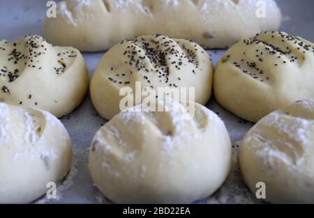Homemade food concept. Preparation process, raw unbaked buns and bread with seeds ready for baking on baking paper. Closeup, copy space. Stock Photo