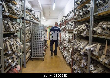 06 April 2020, Saxony-Anhalt, Arneburg: A firefighter from the Stendal District Fire Service Technical Centre (FTZ) walks through a warehouse full of fire hoses. In the FTZ new hoses are stored and old hoses are checked and washed. In the afternoon the converted hose washing facility of the FTZ was put into operation. The hose washing is basically the washing machine for fire hoses. The FTZ cleans and tests about 10.000 of these fire hoses per year. In the district of Stendal up to 16,000 hoses are in use by the fire brigades. Each hose has to be washed after each deployment. Photo: Klaus-Diet Stock Photo