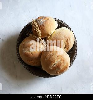 Home baking. Closeup of freshly baked buns on basket and ears of wheat isolated on a white background. Top view Stock Photo