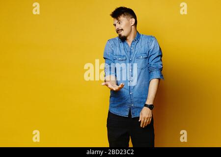 Young handsome man raising one hand with a surprised gesture and looking aside posing over isolated background Stock Photo
