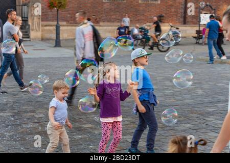Children chasing bubbles in Market Square, Wroclaw, Poland Stock Photo