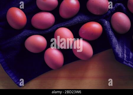 Closeup of pink colored eggs on a towel in the kitchen during the Easter holiday in the spring Stock Photo