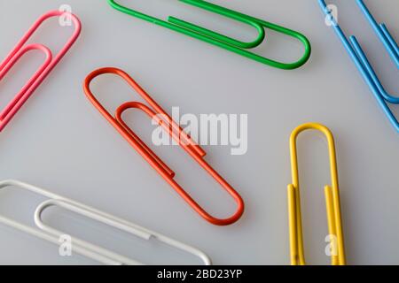 multi colored paper clips on white, gray background. flat lay top view close up Stock Photo