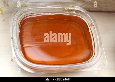 natural honey for sale in plastic containers . honey in a plastic box on a white background . Stock Photo