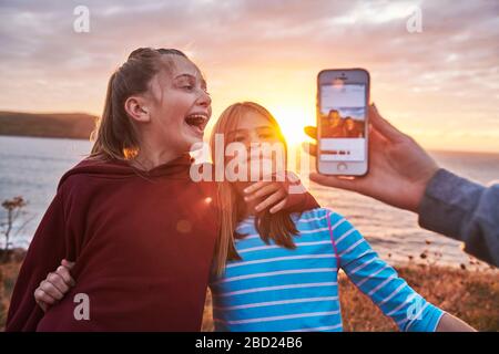 Two young girls looking at a selfie with there mom at sunset. Stock Photo