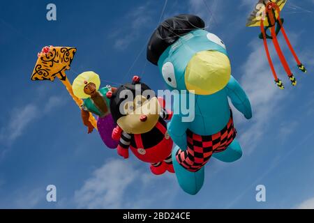 Giant flying cartoon character kites at the Southsea kite festival, Portsmouth, UK with blue sky and clouds in the background Stock Photo