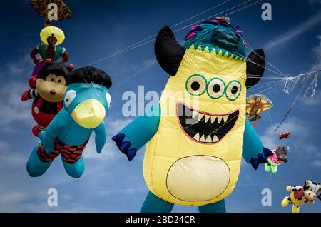 Flying three-eyed monster kite at the Summer Southsea kite festival event, Portsmouth, UK with blue sky and clouds in the background Stock Photo