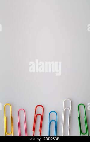 multi colored paper clips on white, gray background. copy space flat lay top view Stock Photo