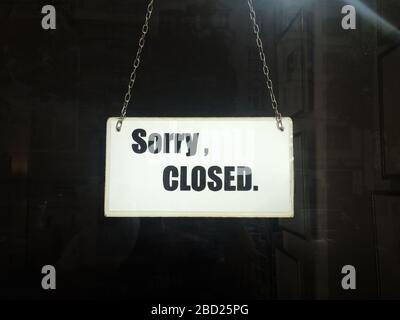 Shutdown. Closed sign of commercial shop in lockdown with Sorry closed typography on cardboard with metal strings hanging in store window Stock Photo