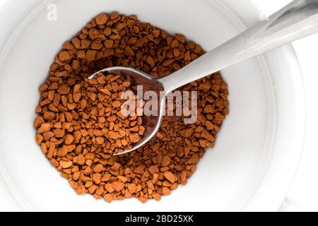 Dry instant coffee in a white ceramic cup with metal spoon. Top view. Stock Photo