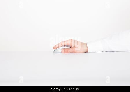 Man's hand is on the modern wireless touch mouse on a white background. Cybersecurity concept. Stock Photo