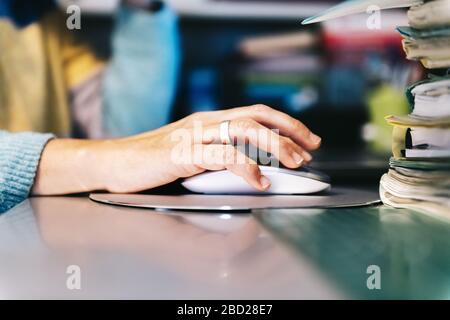 closeup of a female hand clicking computer mouse, technology and teleworking concept, selective focus Stock Photo