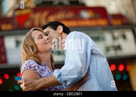 Happy couple embracing outside a movie theater. Stock Photo