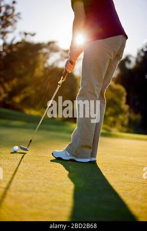 Mid adult woman positioning her golf club to hit the ball. Stock Photo