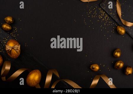 Golden luxury easter eggs and ribbon composition boder frame on black stone background with copy space for text card Stock Photo