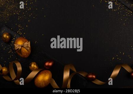 Golden luxury easter eggs and ribbon composition boder frame on black stone background with copy space for text card Stock Photo