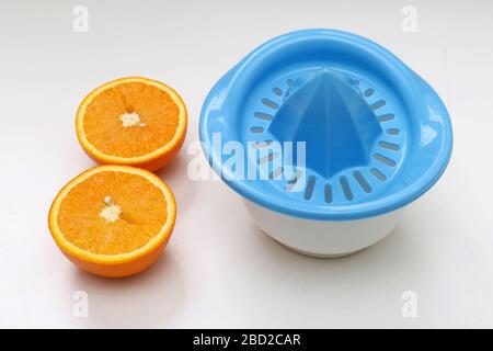 Fresh orange cut in half next to plastic juice squeezer Stock Photo