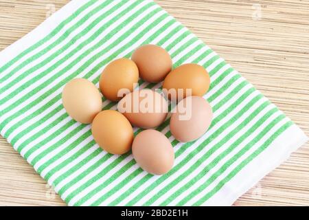 Real farm chicken eggs lie on a green striped napkin and a wooden table Stock Photo