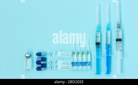 Thermometer, pills, injection ampoules, syringe for vaccination on a blue background, healthcare coronavirus, cancer, painand treatment, pharmaceutica Stock Photo