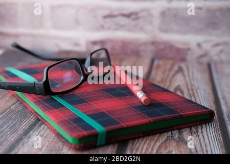 Close up of notepad, pencils, eyeglass on table  Stock Photo