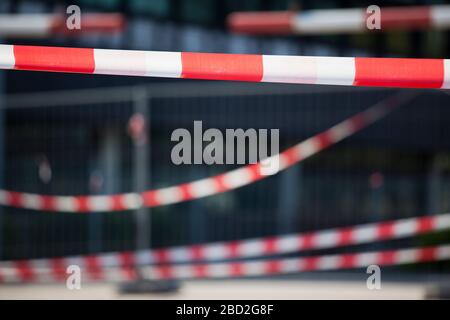 Barrier tapes and fence in front of a building or hospital because of quarantine for covid-19 or crime scene or contstruction site - selective focus Stock Photo
