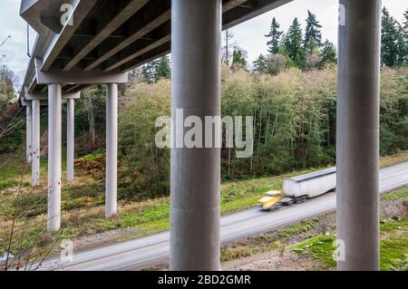 8th Street Bridge in Port Angeles, Washington, as seen from below the span.  A yellow-tractor semi-truck is passing below. Stock Photo