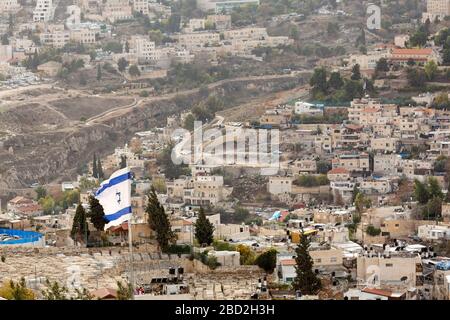 An Israeli flag flutters above the Mount of Olives in Jerusalem, Israel. The Star of David is on the center of the flag. Stock Photo