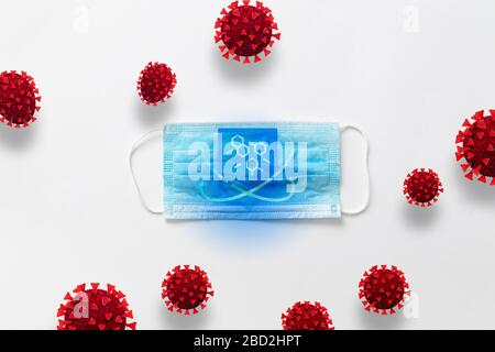Top view of medical mask for protection against polluted air, viruses, bacteria and germs on a gray background with corona virus cells Stock Photo