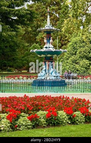 Peacock Fountain, decorative, 3-tier, sculptures, trees, flowers; red geraniums, water, iron fence, Botanical Gardens; Christchurch; New Zealand, sum Stock Photo