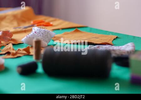 Needle pad on the seamstress table. Seamstress tools. Shallow depth of field. Focus on the needles. Spools of thread are blurred. Horizontal. Stock Photo