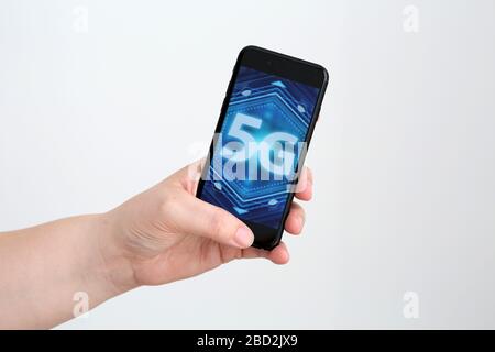 A generic image of a 5g Image/ Logo displayed on a smartphone being held in a hand. Stock Photo