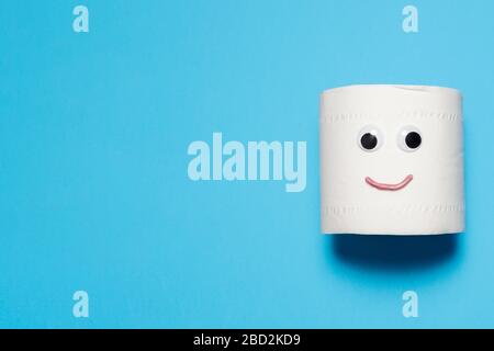 Happy and smiling full roll of toilet paper with googly eyes and mouth on a blue background with copy space and room for text Stock Photo