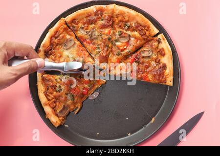 Closeup hand of man cutting pizza at kitchen. Stock Photo