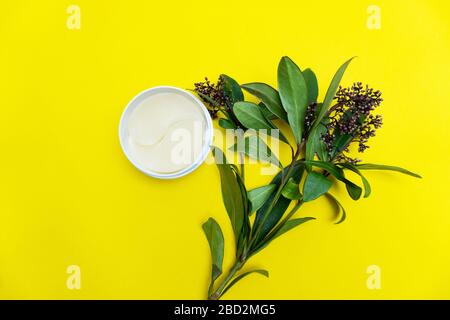 White under eye patches in container near flowers on yellow background Stock Photo