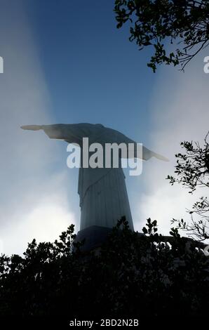 The sun casting shadows onto morning mist as it rises in front of Christ the Redeemer status, Rio De Janerio, Brazil Stock Photo