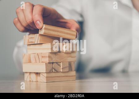 Business plan concept - hands build a tower of wooden blocks. Close up. Stock Photo