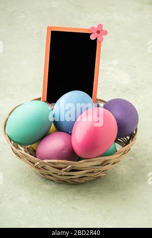 a blank chalkboard on colorfully painted easter eggs on green background Stock Photo