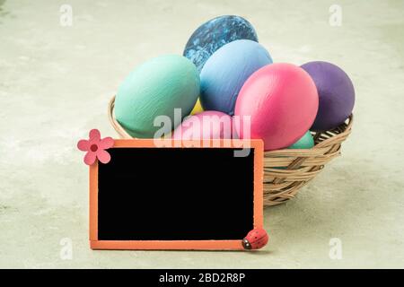 a blank chalkboard on colorfully painted easter eggs on green background Stock Photo