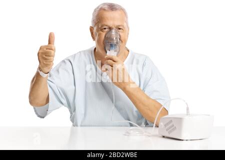 Mature male patient using a nebulizer machine and showing thumbs up isolated on white background Stock Photo