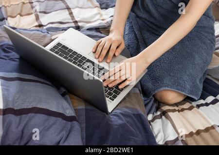 Close up womans hand on the touchpad of a laptop. A young woman are searching in an internet after bath. Using of a notebook in a bedroom. Stock Photo